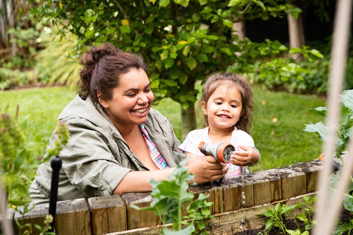 Photo of a mum and her kid watering the garden