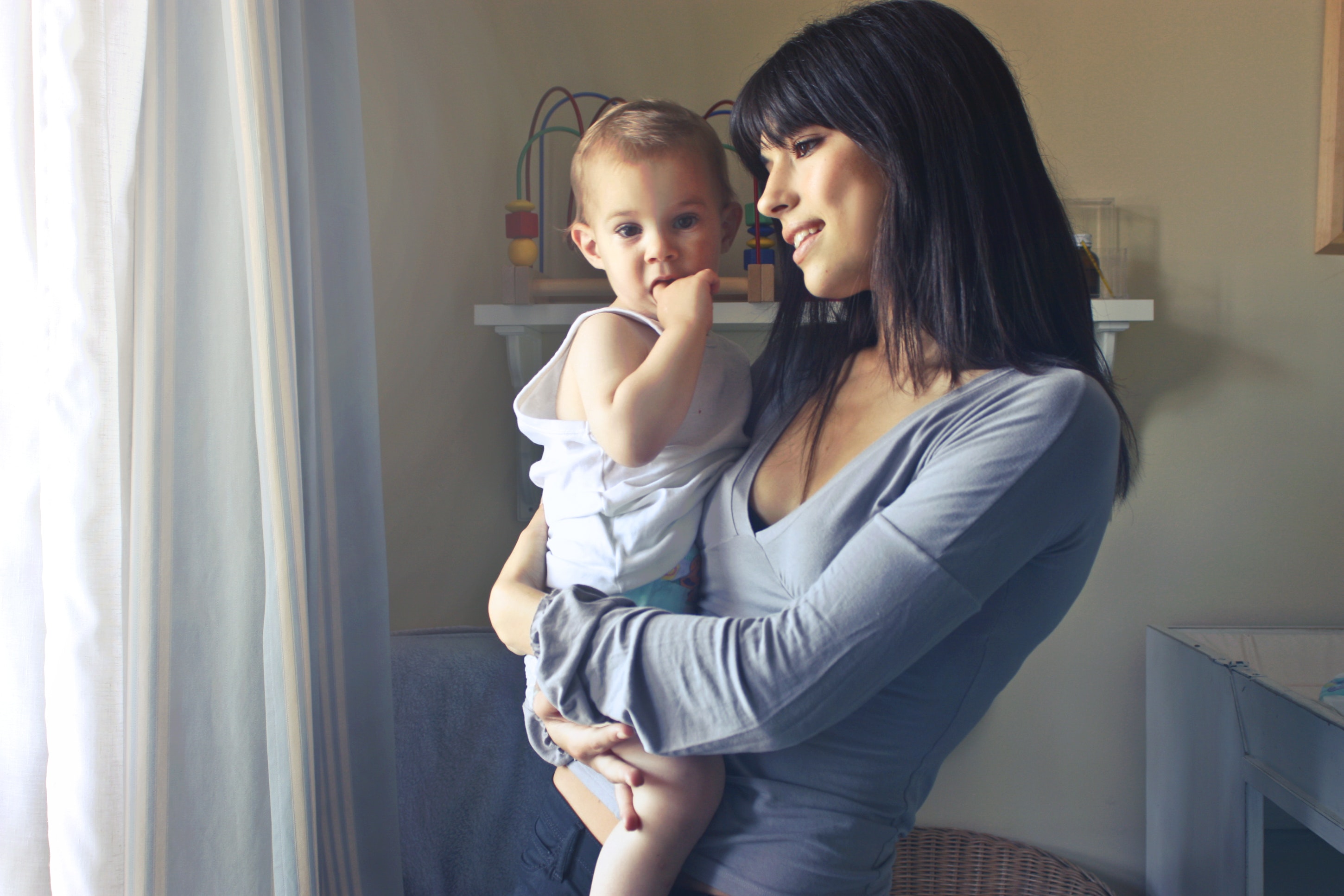 A mother and her baby looking out the window in the nursery