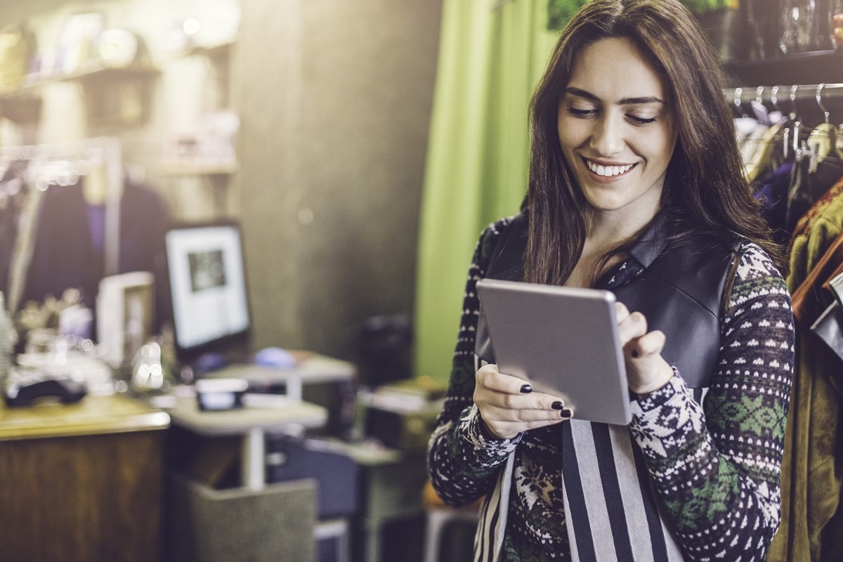 Woman standing up in her home office working on a tablet device.