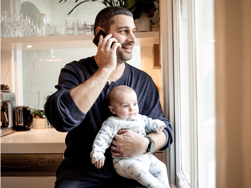 Man holding a baby while using a mobile phone