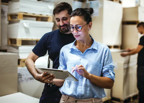 Woman inspecting stock with a tablet while coworker watches 