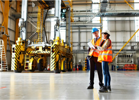 Two workers in high vis walking through a plant looking at a clipboard