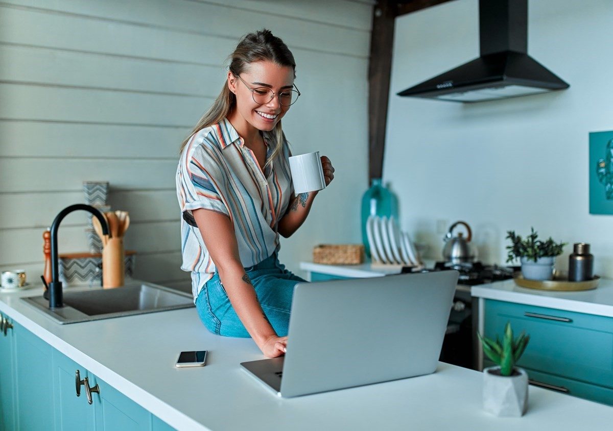 Woman in kitchen using her laptop