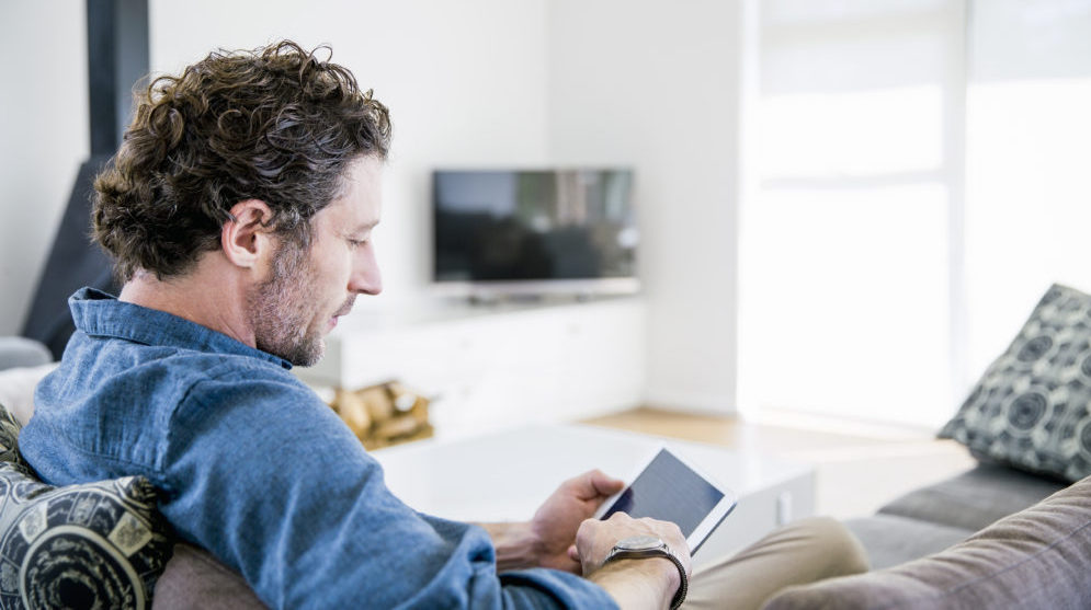 Man sitting on couch looking at an iPad