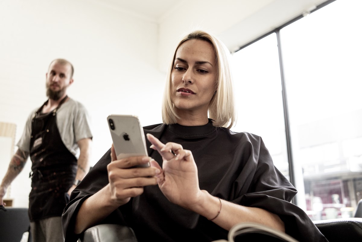 Woman using mobile phone at hairdresser