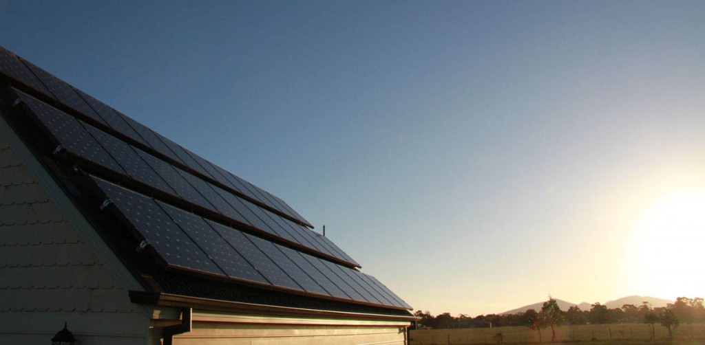 A sunrise going over a house with solar panels