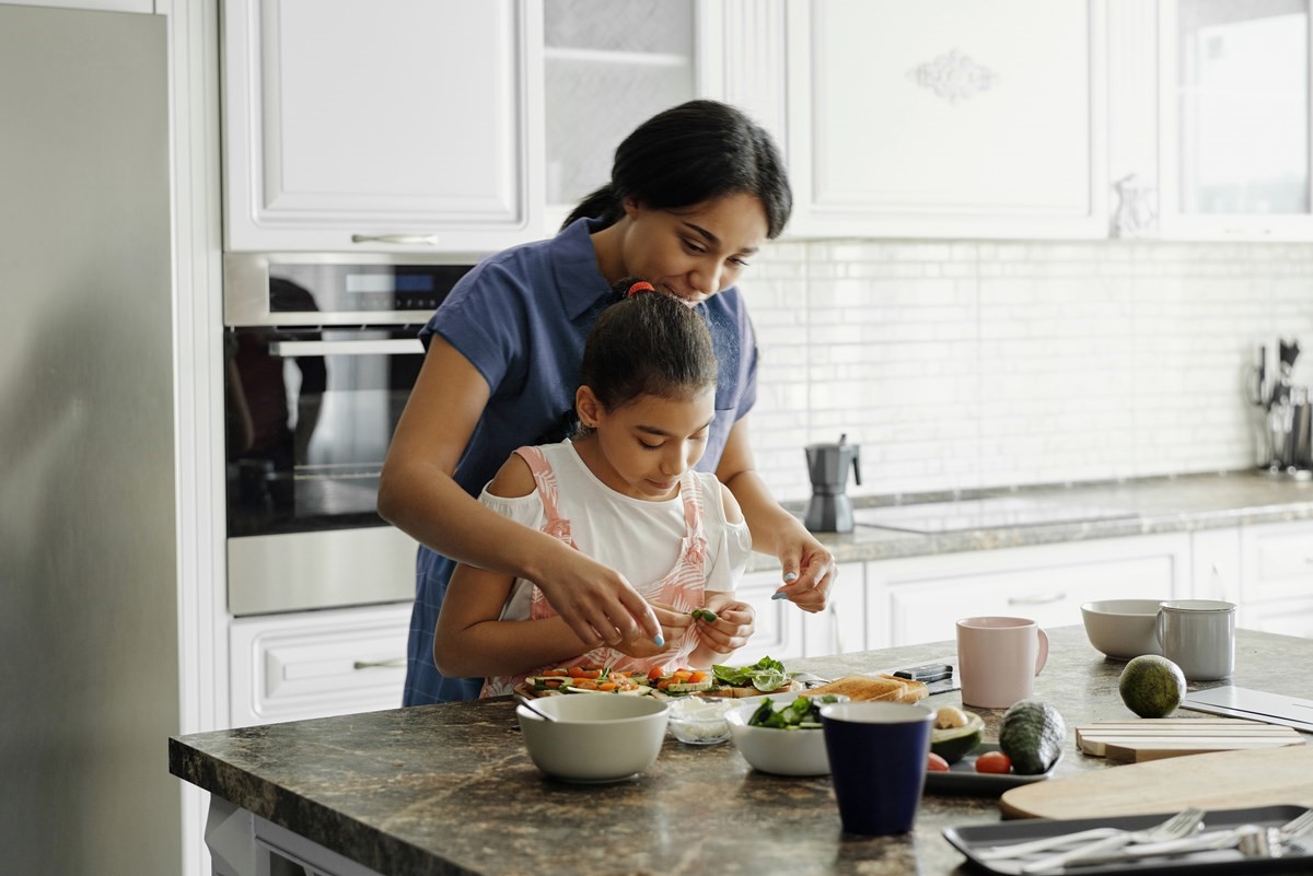 Father and toddler stirring food in a pot